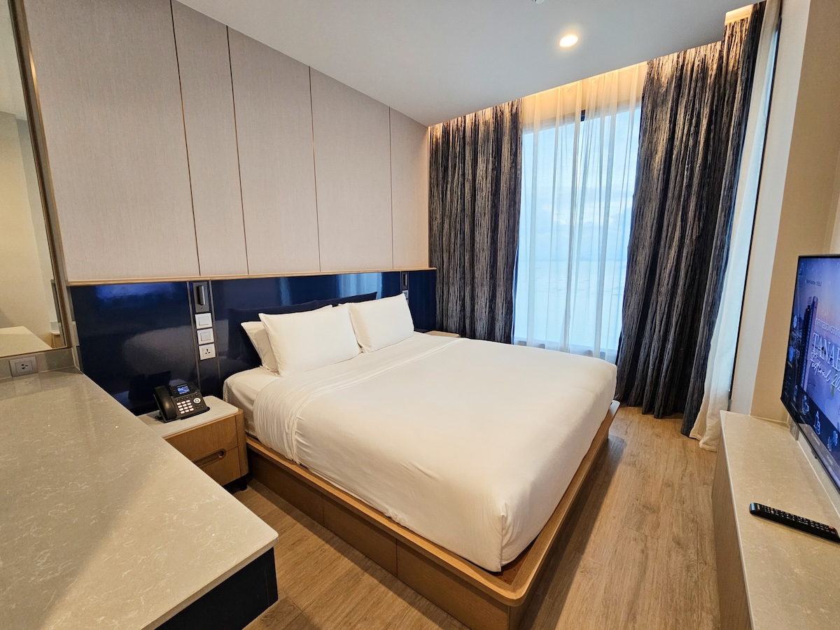 Une chambre d'hôtel confortable avec un lit double, une télévision murale, un bureau, un téléphone et une grande fenêtre avec des rideaux.